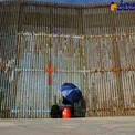 زنی که از پشت نرده های مرز مکزیک و آمریکا با فامیل هایش حرف می زند